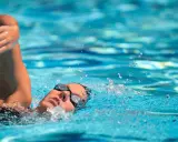 Nuotatore con occhialini, braccio fuori dall'acqua, schizzi che sembrano voler spezzare il fiato.