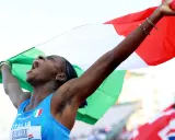 Atleta italiana esulta con la bandiera, un urlo di gioia per il record italiano 100 metri femminile.