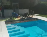 Tecnici al lavoro su una piscina Bestway che perde acqua da sotto, con attrezzature per la riparazione.