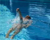 Donna nuota a dorso in una piscina olimpionica, godendosi la profondità e la frescura dell'acqua cristallina.