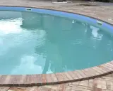 Piscina con acqua torbida e riflessi del cielo, circondata da un bordo in mattoni.