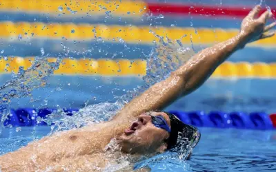 Michele Lamberti in azione, con il braccio teso e l'acqua che schizza, durante una gara di nuoto.