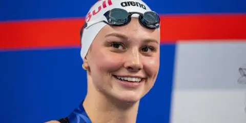 Sorriso raggiante di Summer McIntosh, nuotatrice con cuffia e occhialini, pronta per una gara.