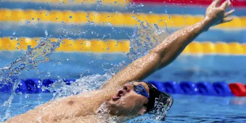 Michele Lamberti in azione, con il braccio teso e l'acqua che schizza, durante una gara di nuoto.