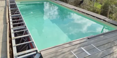 Struttura metallica a vista per piscina fuori terra, con pannelli in legno in fase di posa. Si nota un leggero cedimento della struttura.