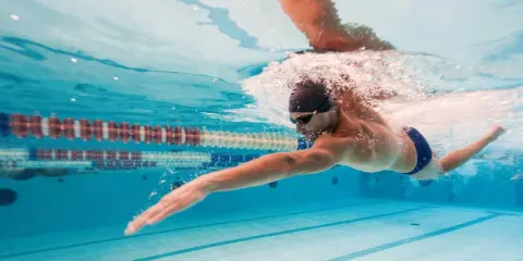 Nuotatore in azione, un'ottima dimostrazione che il nuoto fa dimagrire. L'acqua cristallina della piscina riflette la sua determinazione.