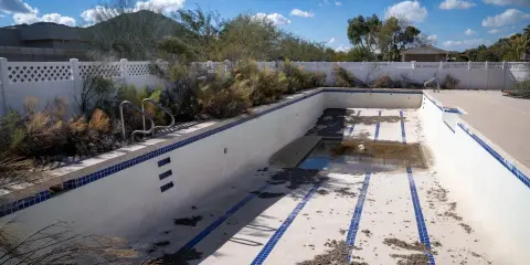 Piscina vuota e sporca, con detriti sul fondo. Immagina come svuotare la piscina con la pompa a sabbia per riportarla al suo antico splendore.