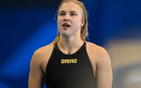 Rūta Meilutytė, nuotolinė plaukikė, su vandens lašeliais ant odos, pasirengusi varžyboms.