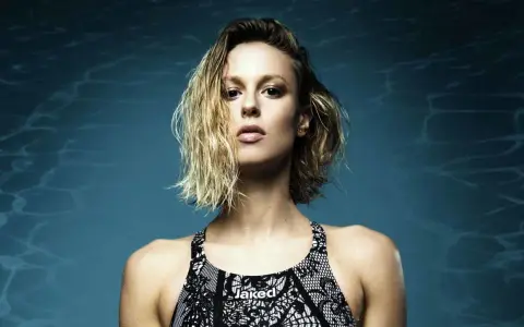 Francesca Pellegrini, nuotatrice con capelli bagnati e costume Jaked, posa con sguardo intenso su sfondo blu con riflessi d'acqua.
