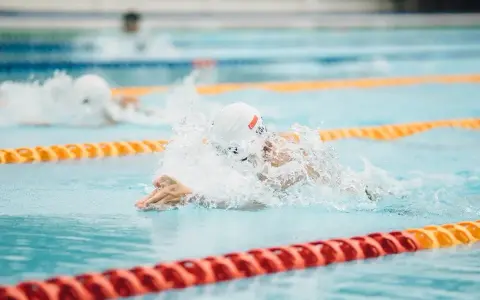 Nuotatore in azione, concentrato su come nuotare più veloce. Schizzi d'acqua e bracciate potenti in piscina.