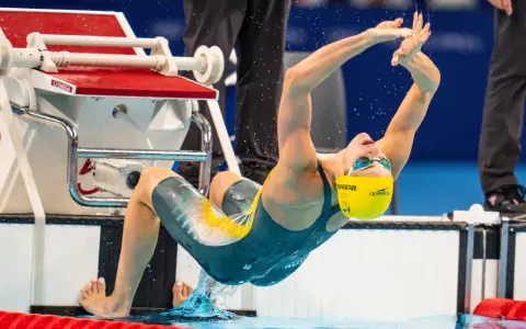 Kaylee McKeown si tuffa in piscina, con le braccia tese e il corpo inarcato, pronta a iniziare la sua gara.