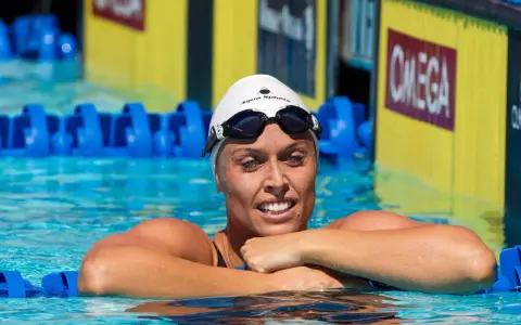 Amanda Beard, nuotatrice sorridente in piscina, con cuffia e occhialini, pronta per la gara.