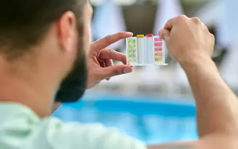 Uomo controlla il kit per acidificare l'acqua della piscina, analizzando i livelli di pH e cloro.