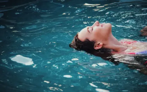 Donna galleggia serena, un passo verso come vincere la paura dell'acqua da adulti. L'acqua turchese la culla, simbolo di pace ritrovata.