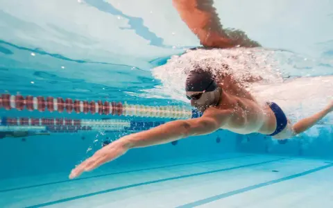 Un uomo nuota a stile libero in piscina, un ottimo modo per capire quanto nuotare per dimagrire e mantenersi in forma.