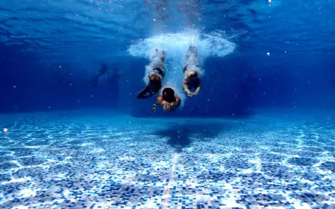 Subacquea, tre persone si tuffano in piscina. Chissà in quanto tempo un adulto impara a nuotare, ma loro sembrano già a loro agio.