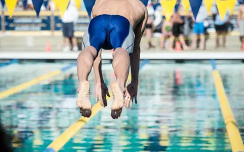 Nuotatore in partenza, dimostrazione dei benefici del nuoto a 50 anni.
