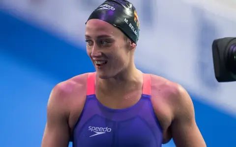 Mireia Belmonte, bagnata e sorridente, indossa un costume da nuoto viola e una cuffia nera.