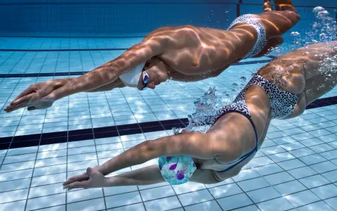 Due nuotatori si allenano in piscina, un uomo e una donna, in un intenso allenamento ipossico.