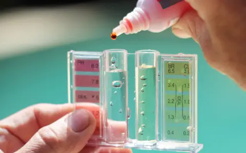 Controllo del pH della piscina: una goccia di reagente cade nel tester per misurare i livelli.