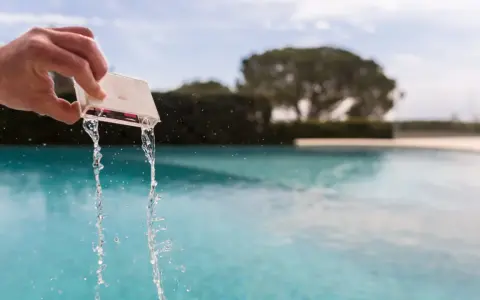 Mano che versa acqua da un contenitore per testare il cloro della piscina.