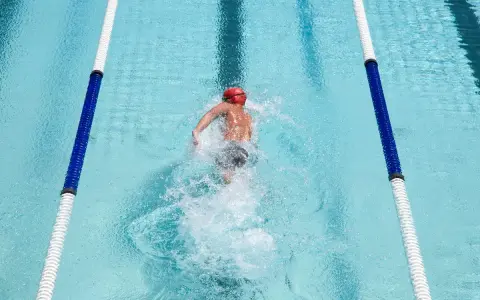 Nuotatore in corsia, godendosi i benefici del nuoto libero. L'acqua cristallina e il movimento fluido del corpo evidenziano la libertà e il benessere.