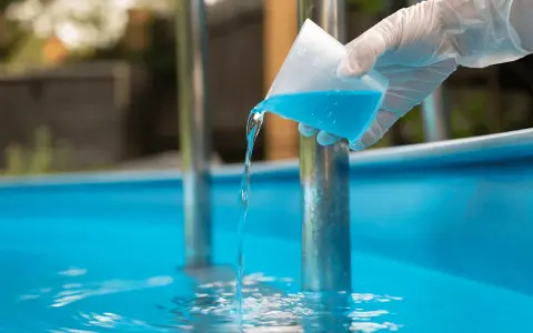 Versando antialghe piscina. Dopo quanto fare il bagno? La soluzione azzurra cade in acqua limpida.