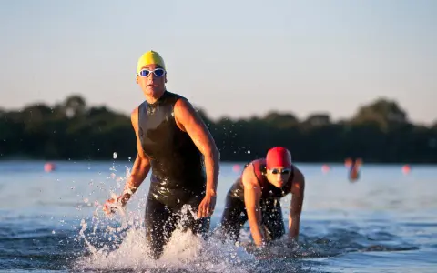 Atleti in muta escono dall'acqua, pronti per la corsa dopo il nuoto.