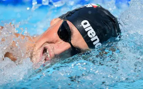 Nuotatore con cuffia Arena e occhialini, immerso nell'acqua con spruzzi. Potrebbe essere Pasquale Giordano in azione.