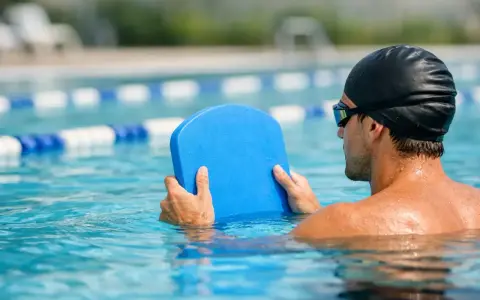 Uomo in piscina con tavoletta blu, pronto per il nuoto con tavoletta per dimagrire.
