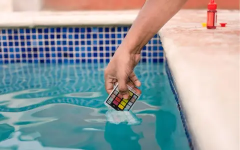 Mano immerge kit test pH nell'acqua della piscina, per assicurarsi che non sia acqua viscida.