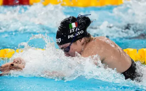 Chiara della Corte, nuotatrice italiana, in azione, con la bandiera tricolore sul costume.