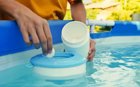 Mano inserisce una pastiglia nel galleggiante per la piscina. Un modo semplice per capire come pulire il filtro della piscina.