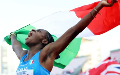 Atleta italiana esulta con la bandiera, un urlo di gioia per il record italiano 100 metri femminile.