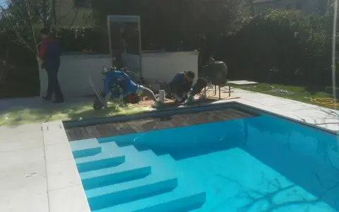Tecnici al lavoro su una piscina Bestway che perde acqua da sotto, con attrezzature per la riparazione.