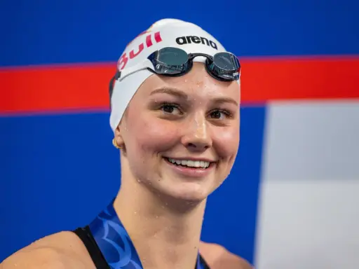 Sorriso raggiante di Summer McIntosh, nuotatrice con cuffia e occhialini, pronta per una gara.