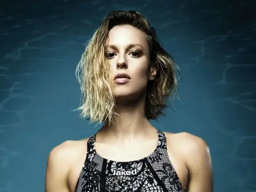 Francesca Pellegrini, nuotatrice con capelli bagnati e costume Jaked, posa con sguardo intenso su sfondo blu con riflessi d'acqua.