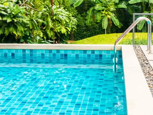 Piscina fuori terra con piastrelle blu scintillanti e vegetazione lussureggiante. La manutenzione piscina fuori terra è fondamentale per godersi questo angolo di paradiso.