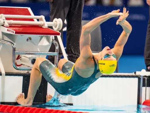 Kaylee McKeown si tuffa in piscina, con le braccia tese e il corpo inarcato, pronta a iniziare la sua gara.