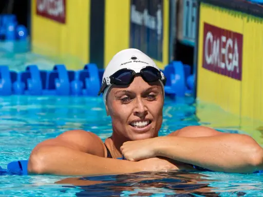 Amanda Beard, nuotatrice sorridente in piscina, con cuffia e occhialini, pronta per la gara.