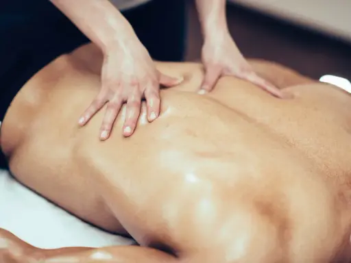 Mani esperte massaggiano la schiena di un nuotatore, sciogliendo la tensione muscolare dopo un allenamento intenso.