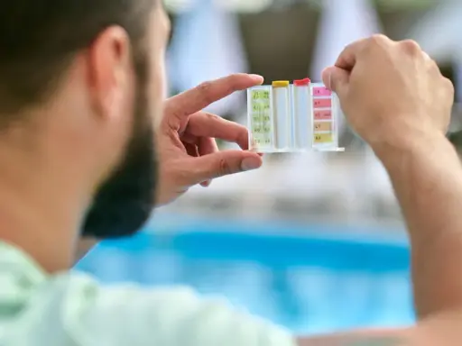 Uomo controlla il kit per acidificare l'acqua della piscina, analizzando i livelli di pH e cloro.