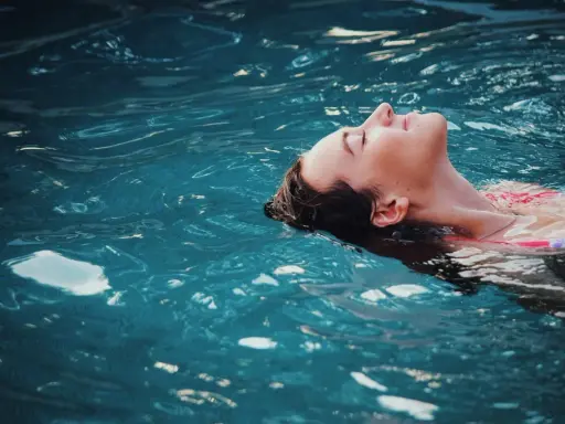 Donna galleggia serena, un passo verso come vincere la paura dell'acqua da adulti. L'acqua turchese la culla, simbolo di pace ritrovata.
