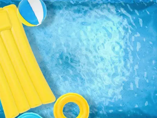 Un materassino giallo, una palla e un salvagente galleggiano in una piscina azzurra. Ideale per scoprire come pulire piscina gonfiabile.