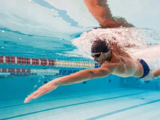 Un uomo nuota a stile libero in piscina, un ottimo modo per capire quanto nuotare per dimagrire e mantenersi in forma.
