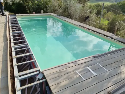Struttura metallica a vista per piscina fuori terra, con pannelli in legno in fase di posa. Si nota un leggero cedimento della struttura.