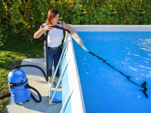 Donna pulisce la piscina con un aspiratore, preparandola per la riapertura dopo l'inverno.
