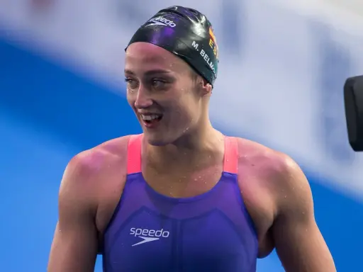 Mireia Belmonte, bagnata e sorridente, indossa un costume da nuoto viola e una cuffia nera.
