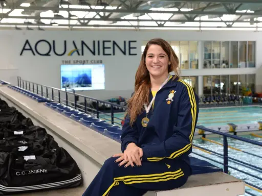 Rachele Ceracchi, nuotatrice sorridente con medaglia al collo, posa in un centro sportivo con piscina.