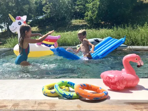 Bambini si divertono in piscina con gonfiabili colorati, tra cui un unicorno e un fenicottero. Perfetti giochi da fare in piscina senza niente per un'estate indimenticabile.